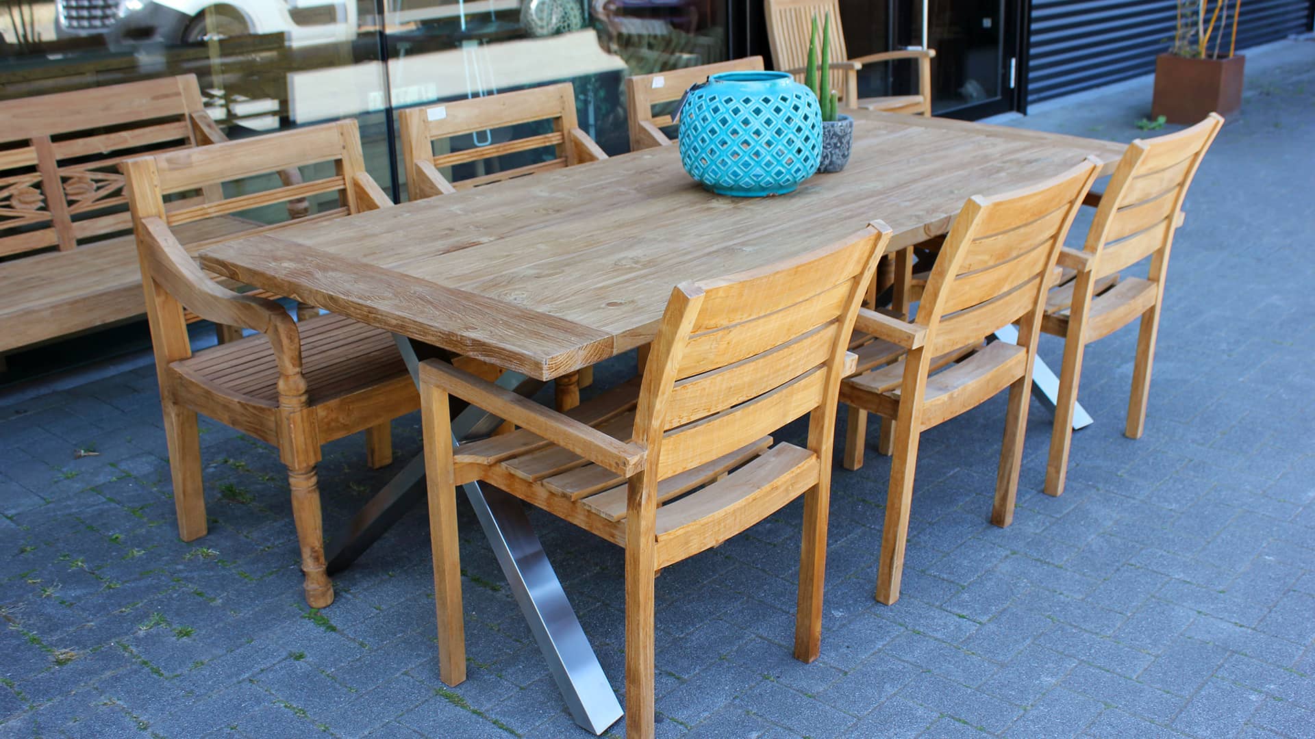 Moderne teakhouten tuintafel met metalen X-poot.